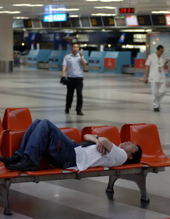 A man lies on chairs at the Haikou Meilan International Airport in Haikou, capital of South China&apos;s Hainan province, as some flights had been canceled due to Typhoon Chanthu Thursday, July 22, 2010. [Xinhua]