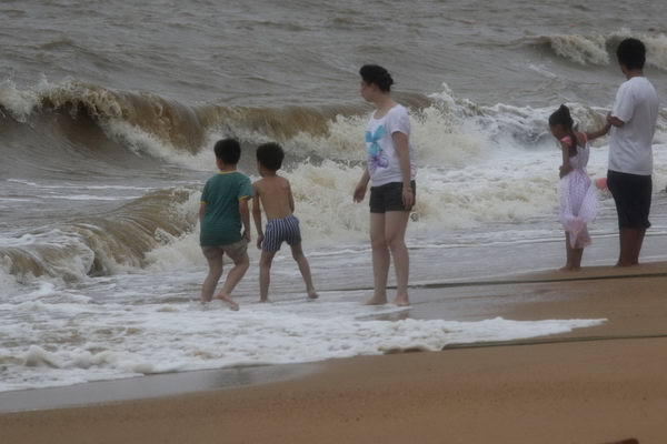 People brave the surge in waves caused by Typhoon Chanthu in Zhuhai, South China&apos;s Guangdong province on July 22, 2010. [Xihua]