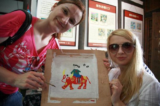 Foreign visitors show up a rural painting drawn by themselves in Fengjing Township in east China's Shanghai, July 22, 2010. Around 100 representatives of working staff of international participants of World Expo 2010, visited the town, famous for rural paintings to experience the Chinese rural culture on Thursday. [Xinhua photo]