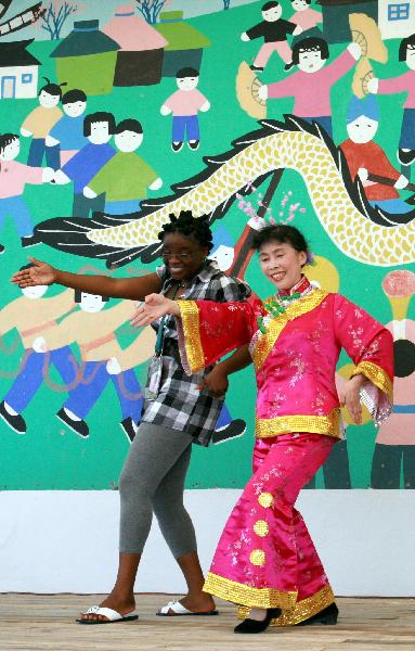 A foreign visitor learns local dance from a villager in Fengjing Township in east China's Shanghai, July 22, 2010. [Xinhua photo]