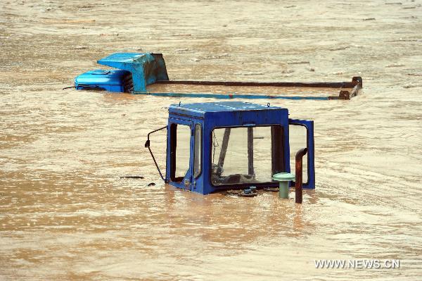 A track loader and a freight car are submerged by floodwaters in Song County, central China's Henan Province, July 24, 2010. A heavy rainstorm hit the Yuxi mountain area in Henan Province from Friday to Saturday. Rain-triggered floods have killed four people and left two missing in Luanchuan County. Communication was also interrupted in some areas of Henan. (Xinhua/Gao Shanyue)