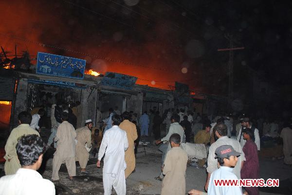 People gather around the blast site in southwest Pakistan's Quetta on July 25, 2010. Over 100 shops caught fire following two gas cylinder explosions which occurred late Sunday night in Quetta.[Iqbal Hussain/Xinhua]