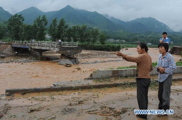 Residents stand in front of the collapsed Koujiagou bridge in Shanyang County, northwest China's Shaanxi Province, July 25, 2010. [Xinhua]