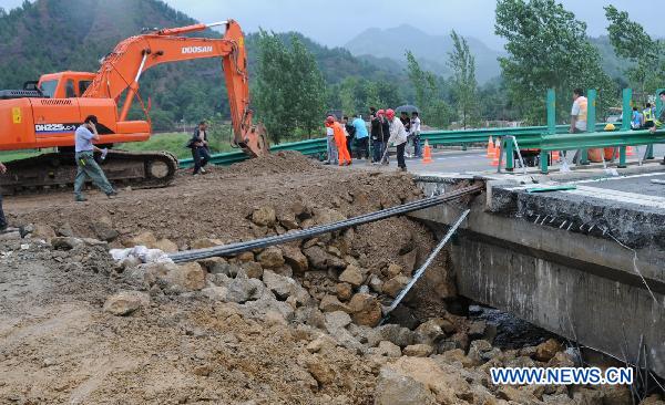Workers repair the flood-destroyed Fuzhou-Yinchuan expressway in the section of Shanyang County, northwest China's Shaanxi Province, July 25, 2010. [Xinhua]