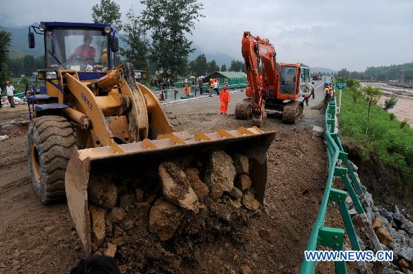 Workers repair the flood-destroyed Fuzhou-Yinchuan expressway in the section of Shanyang County, northwest China's Shaanxi Province, July 25, 2010. [Xinhua]