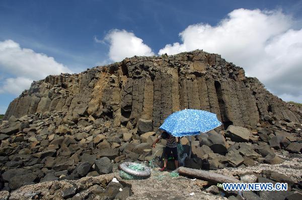 A fisherman settles his fishing net by the side of columnar basalt located in Penghu County of southeast China's Taiwan, July 24, 2010. The natural wonder attracted tourists from all around the world. 