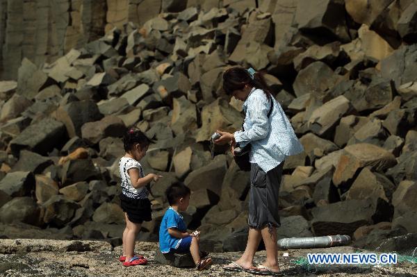 Photo taken on July 24, 2010 shows tourists play with rotten columnar basalt located in Penghu County of southeast China's Taiwan. The natural wonder attracted tourists from all around the world. 