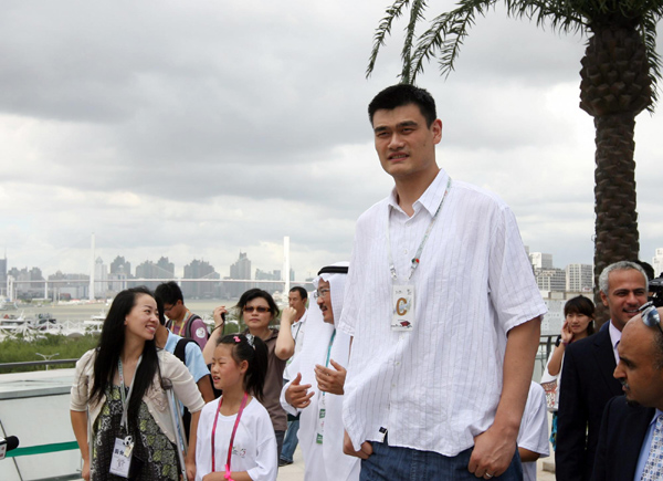 Yao Ming (C) and Jin Jing (L), a Paralympian fencer, leads children from quake-hit regions to visit the roof garden of the Saudi Arabia Pavilion at the Expo Site in Shanghai, July 25, 2010. [Xinhua]