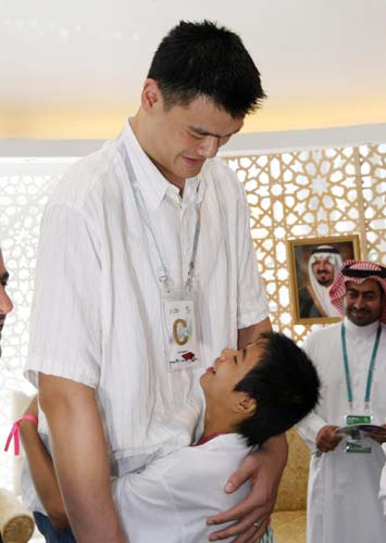 Yao Ming embraces Zhang Peng, a child from the quake-hit Kaixian county of Southwest China’s Chongqing municipality, during his visit to the Saudi Arabia Pavilion at Shanghai World Expo, July 25, 2010. [Xinhua]