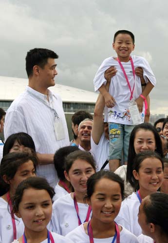 A child is lifted to compare his height with the 2.26-meter Yao as the group poses for photos during a visit to the Saudi Pavilion at Shanghai Expo, July 25, 2010. [Xinhua]