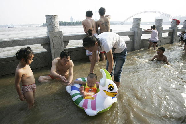 Families have fun in the floodwater in Wuhan, Central China&apos;s Hubei province, July 26, 2010. The continuing downpour has turned the city into a big lake. But it didn&apos;t cause panic. Instead, the aquatic city has become a great treat for people seeking to cool off during the scorching days. [CFP]