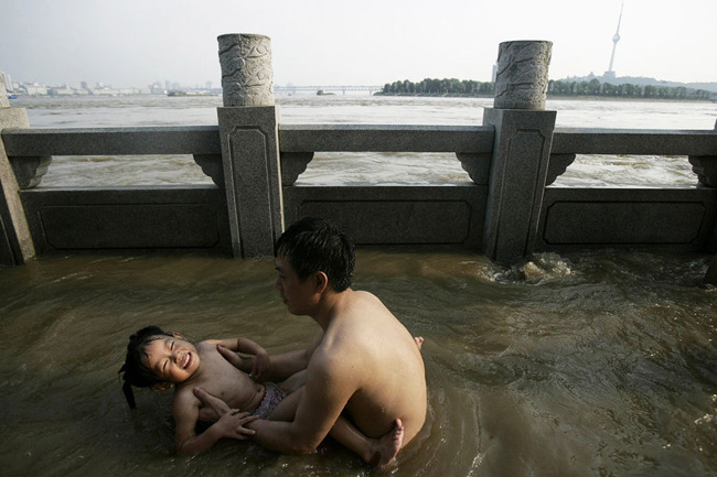 Children frolic in the floodwater to cool down in Wuhan, Central China&apos;s Hubei province, July 26, 2010. [CFP]