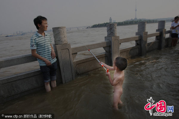 Children frolic in the floodwater to cool down in Wuhan, Central China&apos;s Hubei province, July 26, 2010. [CFP]