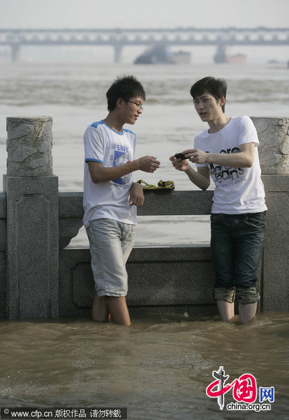 Two men soak their legs in the floodwaters of Wuhan, Central China&apos;s Hubei province, July 26, 2010. [CFP]