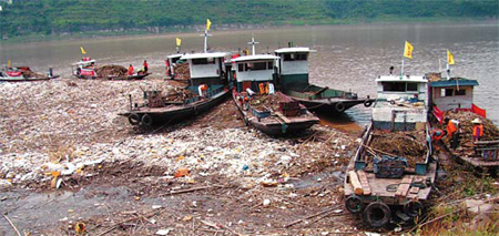 Workers on Monday scoop up trash floating on a section of the upper reaches of the Three Gorges Dam on the Yangtze River, ahead of the second flood peak anticipated in the region. [China Daily]