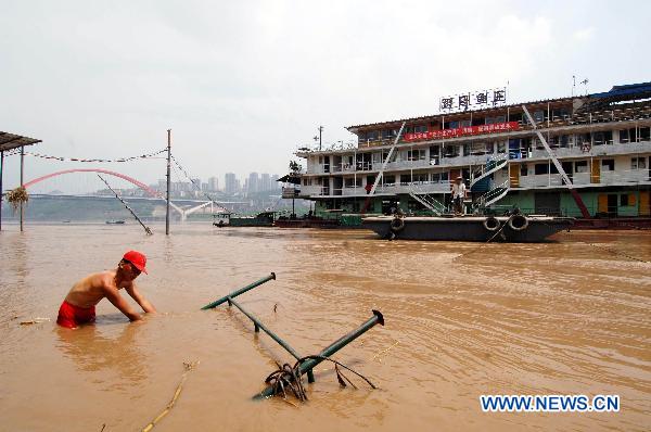 A worker cleans garbage in river channel in southwest China's Chongqing Municipality, July 26, 2010. The Chongqing section of the Yangtze River and Jialingjiang River met the second flood peak of this flood season Monday. [Xinhua] 