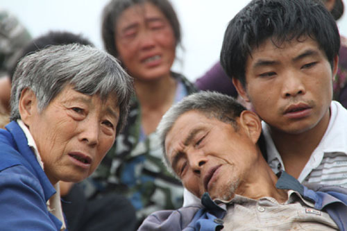 Filled with anxiety, people look at their damaged houses as they wait for rescue workers after the landslide in Hanyan county, Southwest China&apos;s Sichuan province, July 27, 2010. [Xinhua]