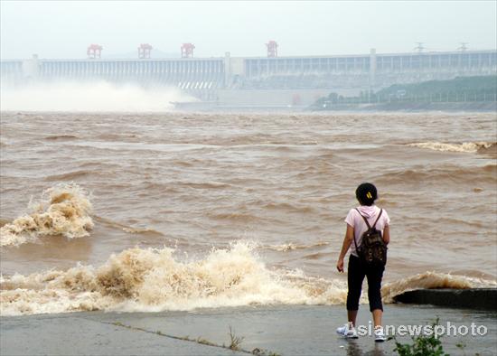 A tourist watches Three Gorges Dam release water along the river in Yichang, Central China's Hubei province on July 27, 2010. [Asianewsphoto]