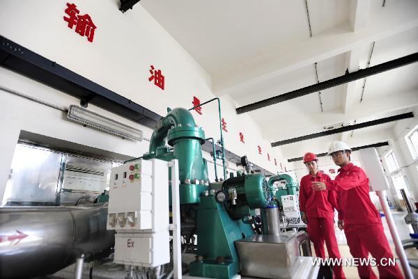 Workers examine the machines in Dalian branch of China National Petroleum Corporation (CNPC) in Dalian, northeast China's Liaoning Province, July 23, 2010. Dalian Xingang Port has resumed providing oil to the factory of Dalian branch of CNPC through the pipelines on July 22. The oil supply from Xingang Port had been stopped since an explosion hit an oil pipeline on July 16 and triggered an adjacent smaller pipeline to explode near the port. [Xinhua] 