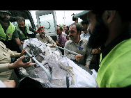 Rescue workers and volunteers recover the body of a victim from an Airblue passenger plane which crashed in Islamabad's Margalla Hills July 28, 2010. [Xinhua]