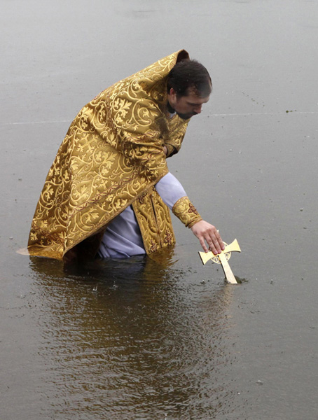 An orthodox priest consecrates water from the Chulym river during a ceremony marking adoption of Christianity, outside Nazarovo town, some 200 km (124 miles) west of the Siberian city of Krasnoyarsk, July 28, 2010. Russia officially celebrated a new holiday on Wednesday marking its conversion to Christianity in 988, the latest Kremlin boost to an Orthodox Church that has grown increasingly powerful since the fall of Communism. [Photo/Agencies]