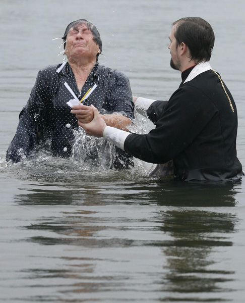 An orthodox priest consecrates water from the Chulym river during a ceremony marking adoption of Christianity, outside Nazarovo town, some 200 km (124 miles) west of the Siberian city of Krasnoyarsk, July 28, 2010. Russia officially celebrated a new holiday on Wednesday marking its conversion to Christianity in 988, the latest Kremlin boost to an Orthodox Church that has grown increasingly powerful since the fall of Communism. [Photo/Agencies]