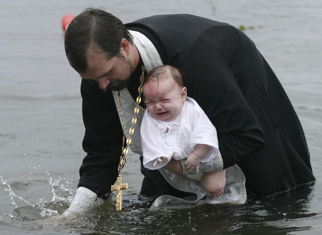 An orthodox priest consecrates water from the Chulym river during a ceremony marking adoption of Christianity, outside Nazarovo town, some 200 km (124 miles) west of the Siberian city of Krasnoyarsk, July 28, 2010. Russia officially celebrated a new holiday on Wednesday marking its conversion to Christianity in 988, the latest Kremlin boost to an Orthodox Church that has grown increasingly powerful since the fall of Communism. [Photo/Agencies]