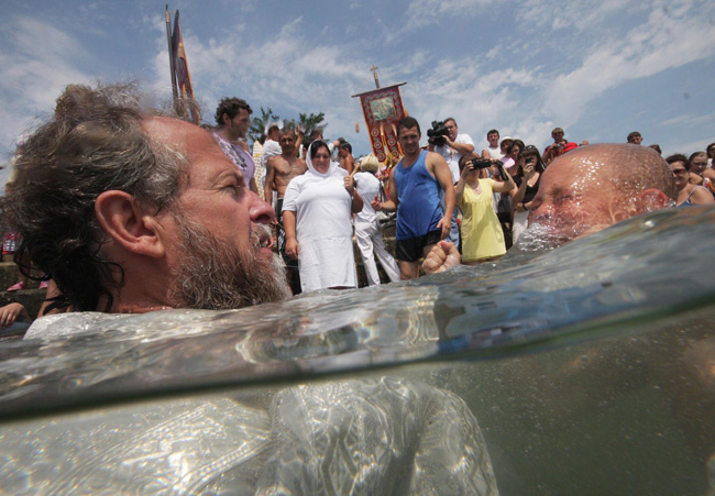 An orthodox priest consecrates water from the Chulym river during a ceremony marking adoption of Christianity, outside Nazarovo town, some 200 km (124 miles) west of the Siberian city of Krasnoyarsk, July 28, 2010. Russia officially celebrated a new holiday on Wednesday marking its conversion to Christianity in 988, the latest Kremlin boost to an Orthodox Church that has grown increasingly powerful since the fall of Communism. [Photo/Agencies]