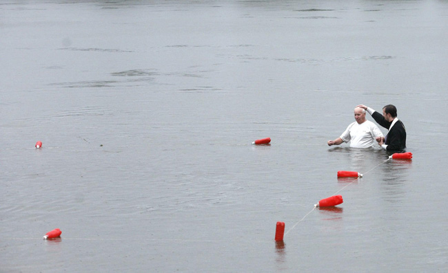 An orthodox priest consecrates water from the Chulym river during a ceremony marking adoption of Christianity, outside Nazarovo town, some 200 km (124 miles) west of the Siberian city of Krasnoyarsk, July 28, 2010. Russia officially celebrated a new holiday on Wednesday marking its conversion to Christianity in 988, the latest Kremlin boost to an Orthodox Church that has grown increasingly powerful since the fall of Communism. [Photo/Agencies]