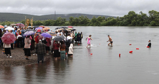 An orthodox priest consecrates water from the Chulym river during a ceremony marking adoption of Christianity, outside Nazarovo town, some 200 km (124 miles) west of the Siberian city of Krasnoyarsk, July 28, 2010. Russia officially celebrated a new holiday on Wednesday marking its conversion to Christianity in 988, the latest Kremlin boost to an Orthodox Church that has grown increasingly powerful since the fall of Communism. [Photo/Agencies]