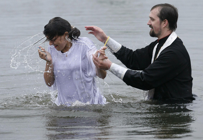 An orthodox priest consecrates water from the Chulym river during a ceremony marking adoption of Christianity, outside Nazarovo town, some 200 km (124 miles) west of the Siberian city of Krasnoyarsk, July 28, 2010. Russia officially celebrated a new holiday on Wednesday marking its conversion to Christianity in 988, the latest Kremlin boost to an Orthodox Church that has grown increasingly powerful since the fall of Communism. [Photo/Agencies]