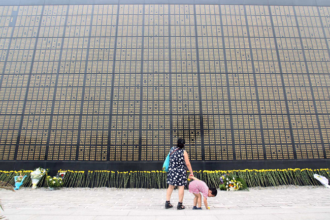 A woman and her child mourn quake victims of Tangshan earthquake in fornt of a 300-meter-long wall, widely known as the Chinese &apos;wailing wall&apos; at Tangshan Earthquake Memorial Park, Hebei Province, July 28, 2010. A 7.8-magnitude earthquake struck north China&apos;s Tangshan on July 28, 1976, lost 240,000 lives. [CFP]