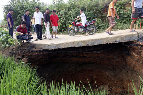 People walk over the land subsidence in Hutang village of Loudi, Central China's Hunan province, July 28, 2010.