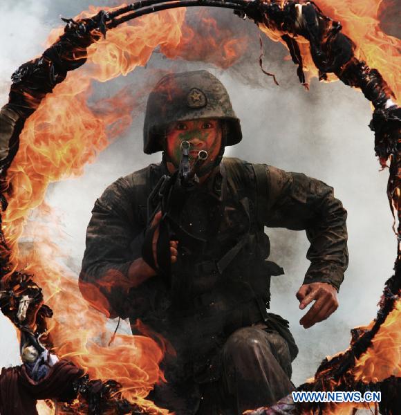A soldier jumps over a fire obstacle during a psychological training at an army training field in Guangzhou, capital of south China's Guangdong Province, July 28, 2010, before the coming 83rd anniversary of the founding of the People's Liberation Army (PLA) which falls on August 1. 