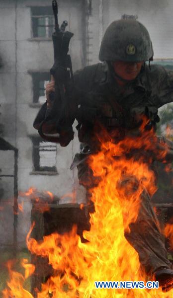 A soldier jumps over a fire obstacle during a psychological training at an army training field in Guangzhou, capital of south China's Guangdong Province, July 28, 2010, before the coming 83rd anniversary of the founding of the People's Liberation Army (PLA) which falls on August 1. 