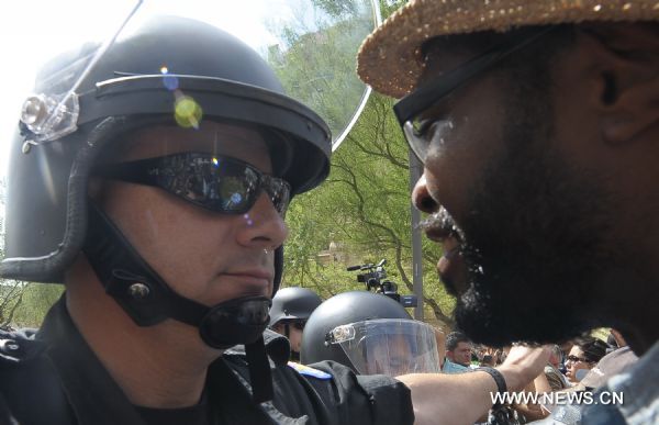 Police stand guard as protestors demonstrate against Arizona&apos;s controversial Senate Bill 1070 immigration law in downtown Phoenix, Arizona, the United States, July 29, 2010. The immigration law takes effect in Arizona on Thursday with some key portions blocked by U.S. District Court Judge Susan Bolton. [Xinhua]