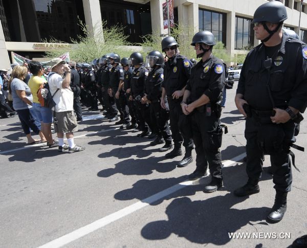 Police stand guard as protestors demonstrate against Arizona&apos;s controversial Senate Bill 1070 immigration law in downtown Phoenix, Arizona, the United States, July 29, 2010. The immigration law takes effect in Arizona on Thursday with some key portions blocked by U.S. District Court Judge Susan Bolton.[Qi Heng/Xinhua]