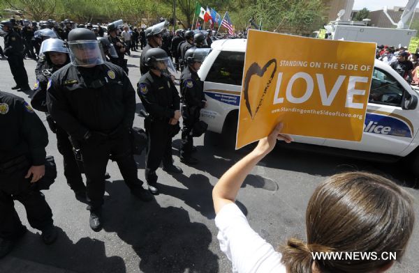 Police stand guard as protestors demonstrate against Arizona&apos;s controversial Senate Bill 1070 immigration law in downtown Phoenix, Arizona, the United States, July 29, 2010. The immigration law takes effect in Arizona on Thursday with some key portions blocked by U.S. District Court Judge Susan Bolton.[Qi Heng/Xinhua]