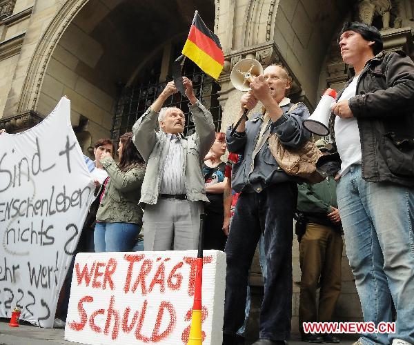 People hold a demonstration outside the city hall in Duisburg, western Germany, on July 29, 2010, to call for the resignation of mayor Adolf Sauerland over the Love Parade disaster, in which 21 people died and more than 500 were injured in a stampede on July 24. [Zhou Gufeng/Xinhua]