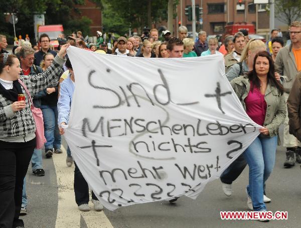 People hold a demonstration outside the city hall in Duisburg, western Germany, on July 29, 2010, to call for the resignation of mayor Adolf Sauerland over the Love Parade disaster, in which 21 people died and more than 500 were injured in a stampede on July 24. [Zhou Gufeng/Xinhua]