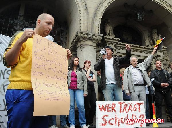 People hold a demonstration outside the city hall in Duisburg, western Germany, on July 29, 2010, to call for the resignation of mayor Adolf Sauerland over the Love Parade disaster, in which 21 people died and more than 500 were injured in a stampede on July 24. [Zhou Gufeng/Xinhua]