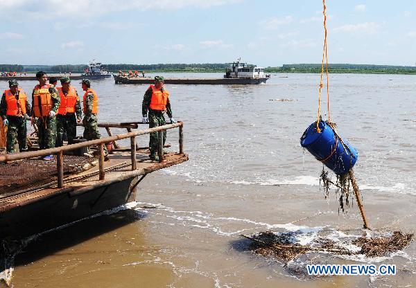 Workers retrieve a chemical container from the Songhua River at the Wukeshu Dock in Yushu City, northeast China's Jilin Province, July 29, 2010. 