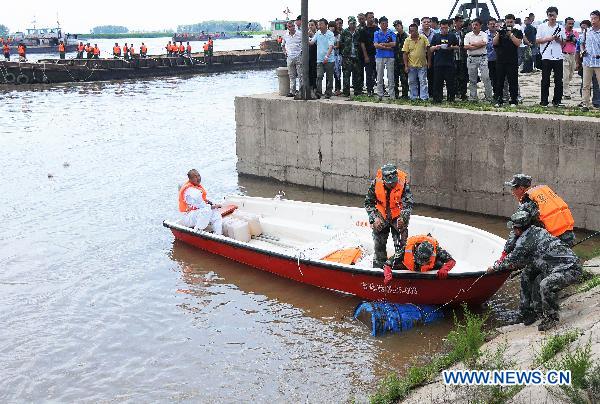 Workers retrieve a chemical container from the Songhua River at the Wukeshu Dock in Yushu City, northeast China's Jilin Province, July 29, 2010.