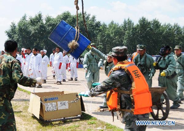 Workers carry away a chemical container collected from the Songhua River at the Wukeshu Dock in Yushu City, northeast China's Jilin Province, July 29, 2010.