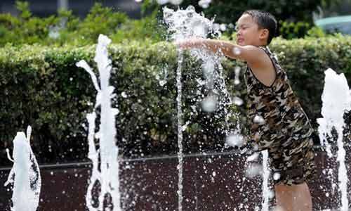 A boy plays in a fountain in downtown Beijing. North China including Beijing and Tianjin has seen muggy weather for the past week with the minimum temperature a notch above average at 35 degrees Celsius. The meteorological observatory said rains were expected later this week. [Photo from Qianlong.com]