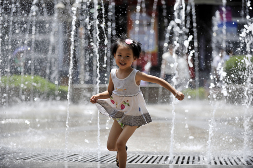 A girl runs through a fountain in downtown Lanzhou, capital of Gansu Province, on Friday, as the mercury rose to 40 C. [China Daily] 