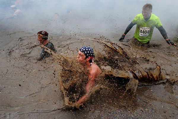 Competitors emerge from muddy water during the Tough Guy Challenge, at South Perton Farm, in Wolverhampton, England, July 25, 2010.