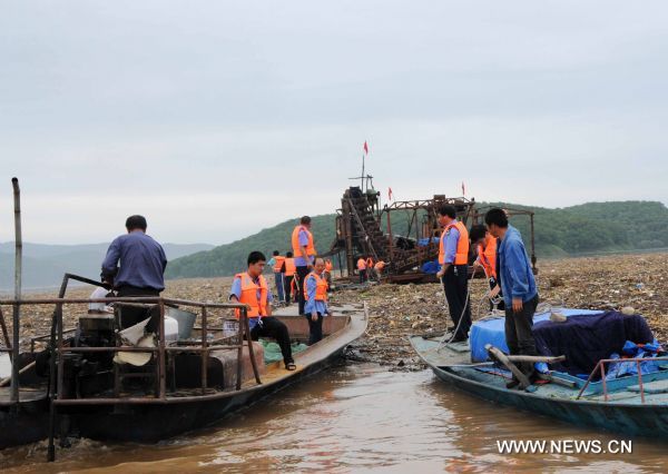 People try to use rope to draw a heavy vessel on the Songhua Lake, northeast China's Jilin Province, July 31, 2010.