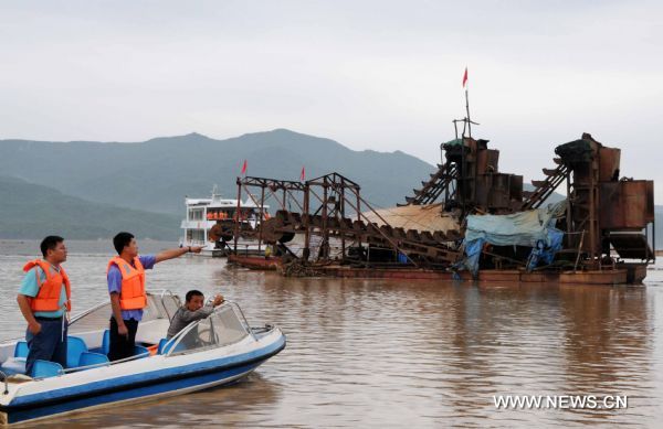 People instruct to draw a heavy vessel to safe place on the Songhua Lake, northeast China's Jilin Province, July 31, 2010.