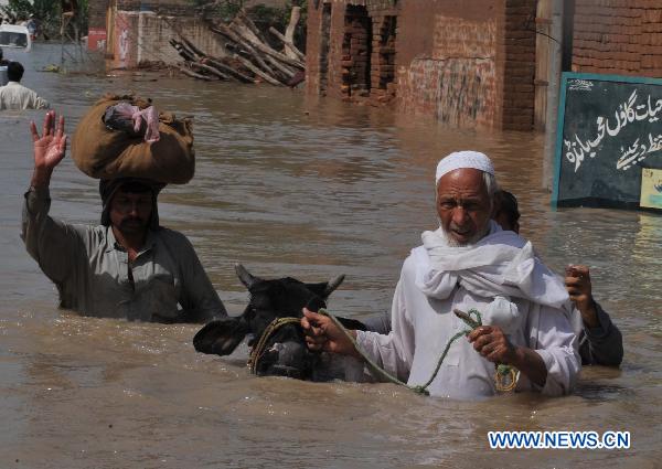 People migrate with their belongings as their houses were flooded following heavy monsoon rains in northwest Pakistan's Pabbi, on July 31, 2010.